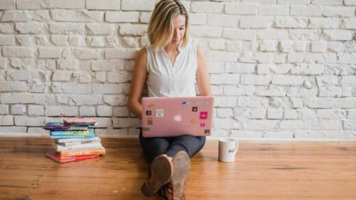 Influencerin sitzt auf dem Boden und schreibt auf dem Laptop