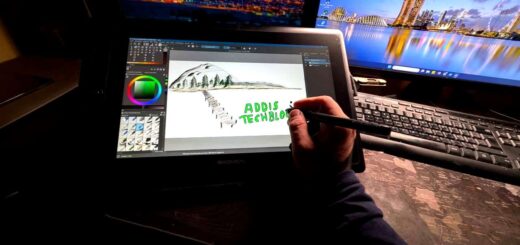 Hand mit Stylus zeichnet auf Gaomon Pen Display Tablet eine Berglandschaft mit Tannen, im Hintergrund zwei Monitore mit Stadtansichten, Zeichensoftware mit Farbrad sichtbar