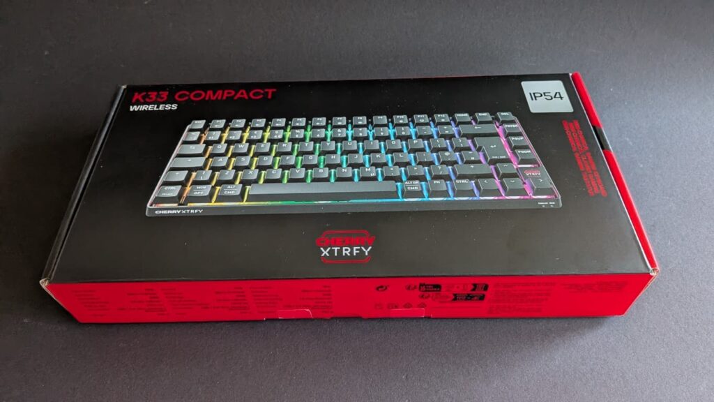 Die Vorderseite der schwarz-roten Originalverpackung der CHERRY XTRFY K33 Compact Wireless Tastatur mit abgebildetem Produkt und IP54-Logo.