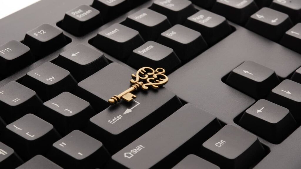 Messingfarbener Schlüssel liegt auf einer schwarzen Computertastatur – Passkey ersetzt das Passwort