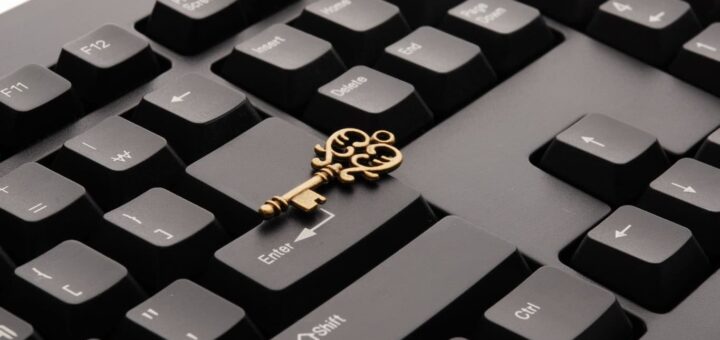 Messingfarbener Schlüssel liegt auf einer schwarzen Computertastatur – Passkey ersetzt das Passwort