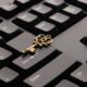 Messingfarbener Schlüssel liegt auf einer schwarzen Computertastatur – Passkey ersetzt das Passwort