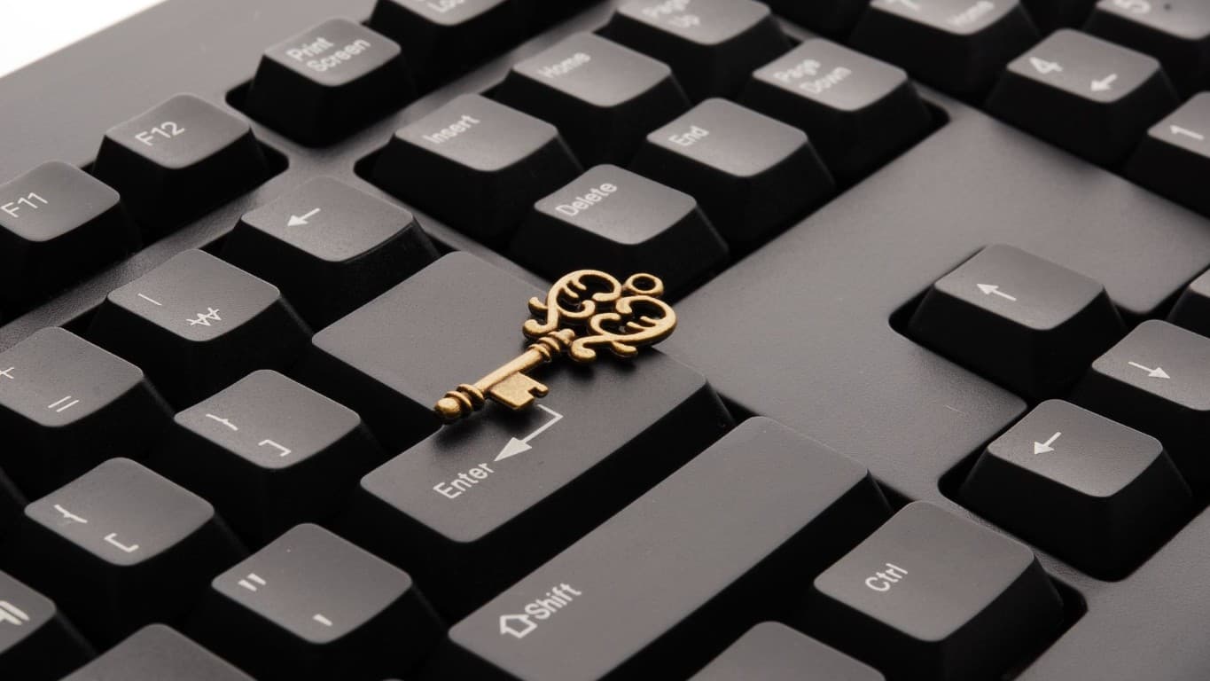 Messingfarbener Schlüssel liegt auf einer schwarzen Computertastatur – Passkey ersetzt das Passwort