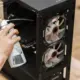 Person reinigt das Innere eines Computergehäuses mit Druckluft