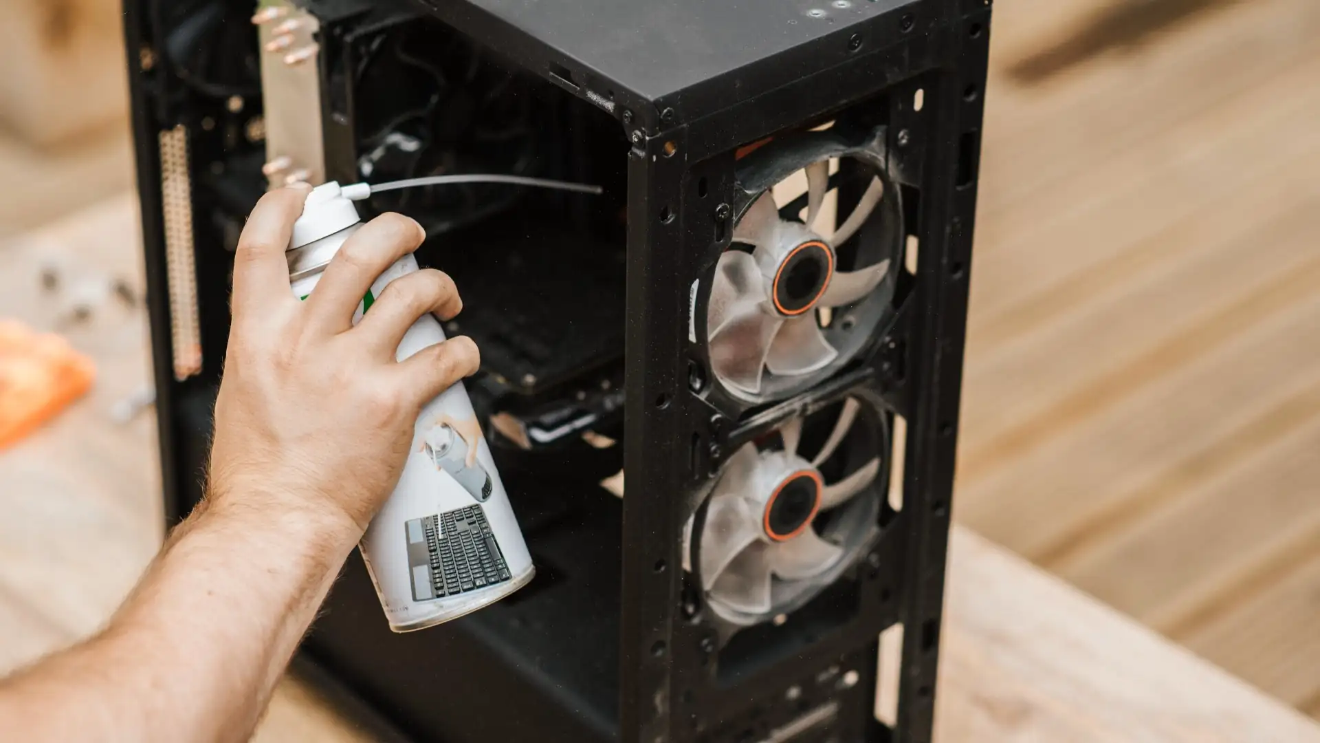Person reinigt das Innere eines Computergehäuses mit Druckluft