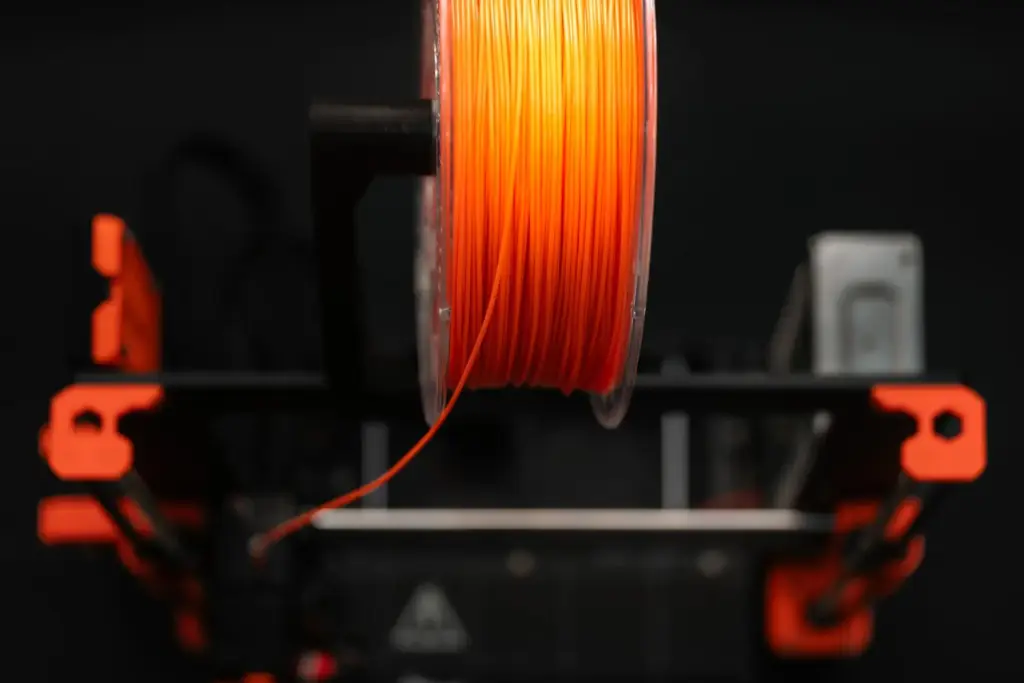 Orangefarbene Filamentspule an der Filamentzuführung eines 3D-Druckers