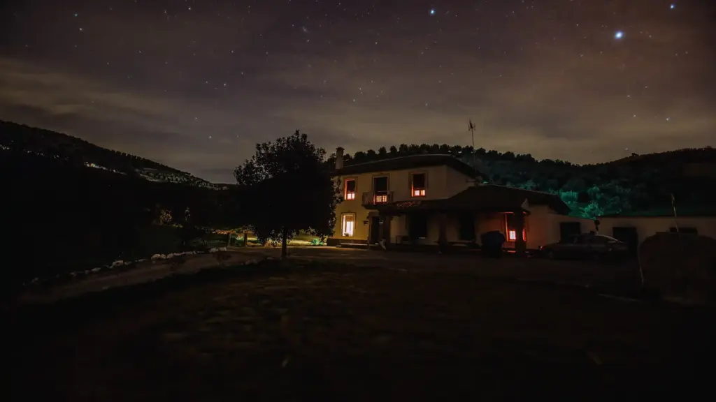 Einzeln stehendes Haus mit warm beleuchteten Fenstern bei Nacht