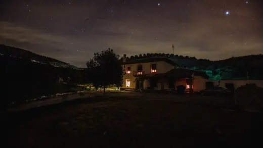 Einzeln stehendes Haus mit warm beleuchteten Fenstern bei Nacht