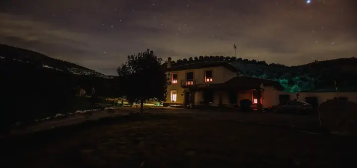 Einzeln stehendes Haus mit warm beleuchteten Fenstern bei Nacht
