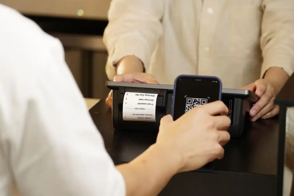 Smartphone scannt QR-Code am Kassendisplay, um den digitalen Kassenbon abzurufen