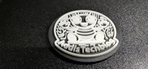 Nahaufnahme eines zweifarbig gedruckten Logo-Untersetzers auf der texturierten Druckplatte, die unteren Schichten sind am Rand sichtbar