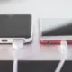 Zwei Smartphones liegen nebeneinander auf einem Tisch und laden per Kabel
