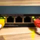 Netzwerk-Switch mit mehreren eingesteckten LAN-Kabeln auf einer Holzoberfläche