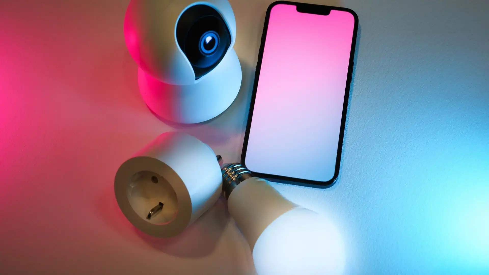 Smarte Kamera und smarte Glühbirne neben einem Smartphone als Steuerzentrale
