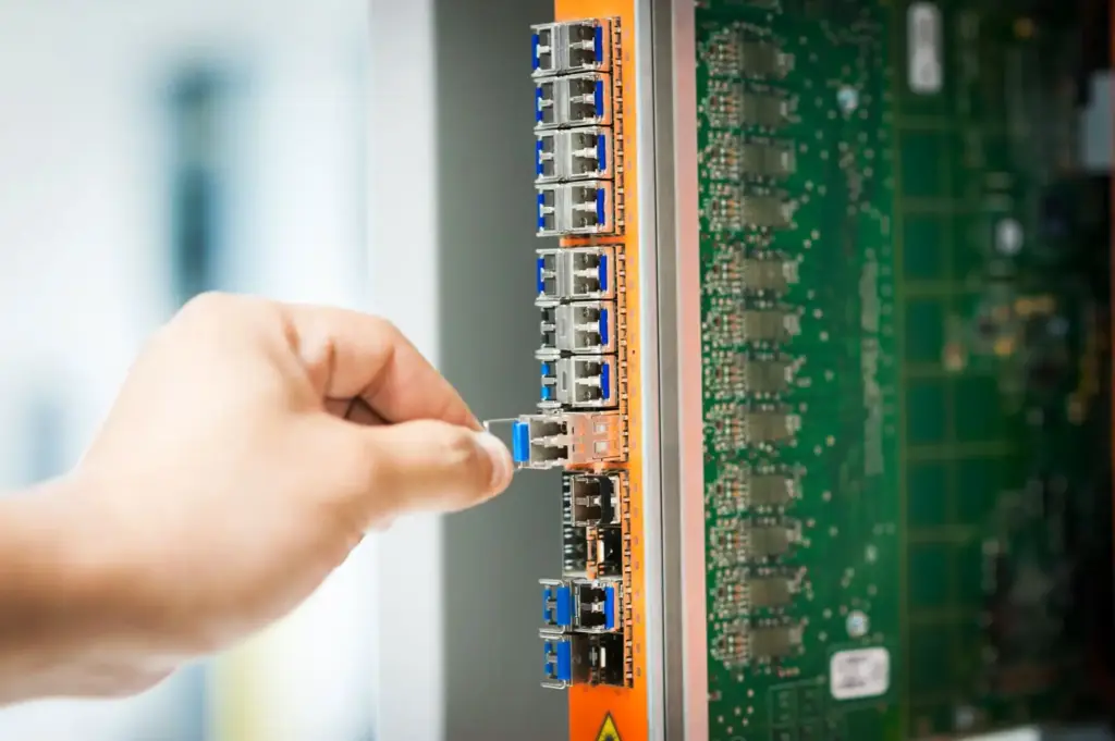 Hand steckt ein Netzwerkkabel in einen Anschluss
