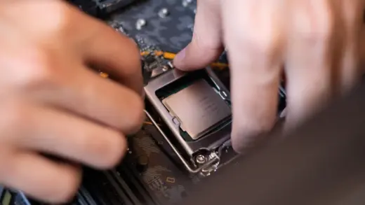 Hände setzen einen Prozessor auf das Mainboard eines PCs