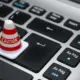 Kleiner weißer Warnkegel auf einer Computertastatur – Symbolbild für den Windows Defender Fehlalarm