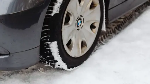 Nahaufnahme eines Autoreifens auf schneebedeckter Straße