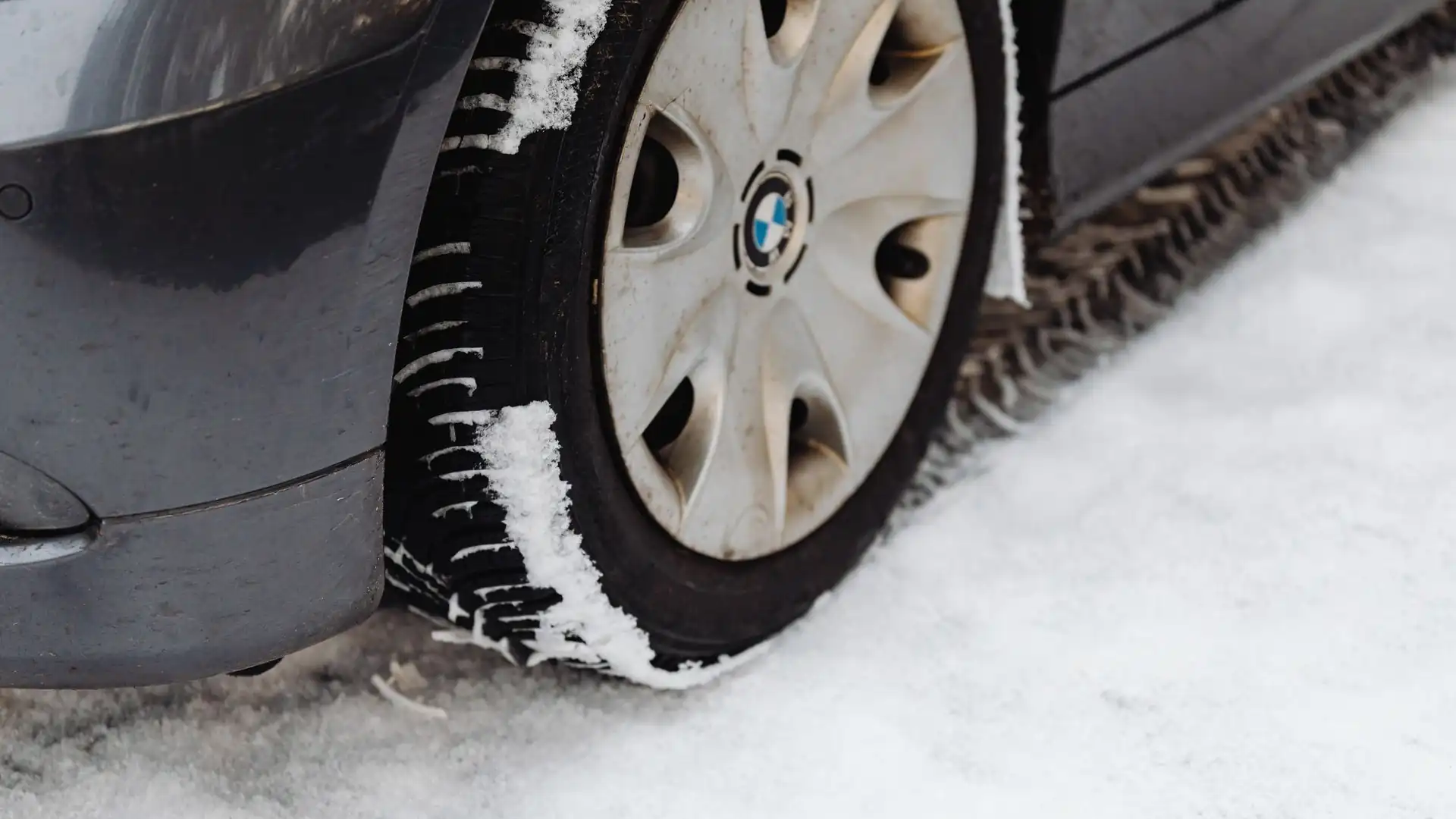 Nahaufnahme eines Autoreifens auf schneebedeckter Straße