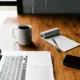 Aufgeräumter Schreibtisch am Morgen mit Laptop, Kaffeetasse und Notizbuch
