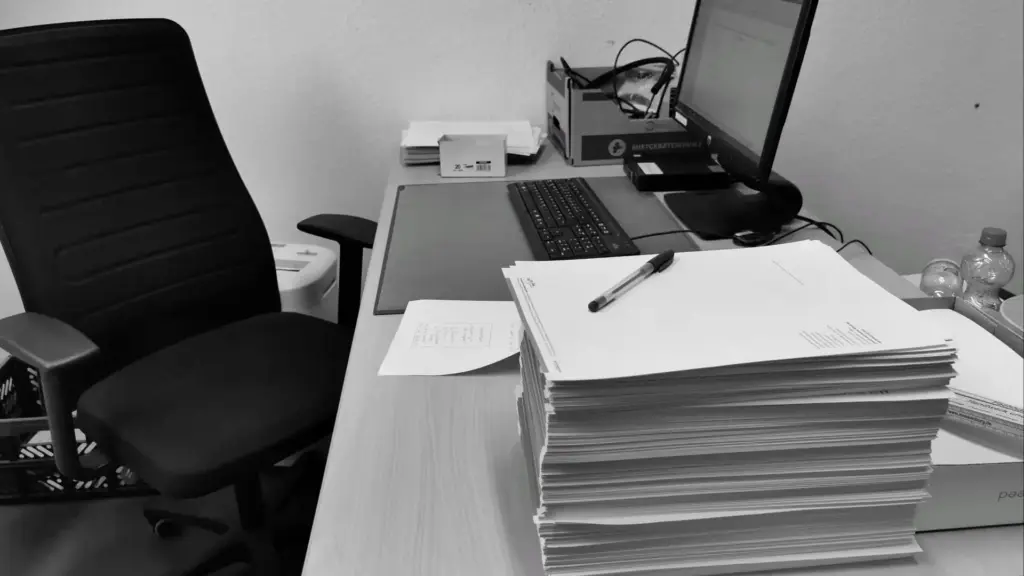 Schreibtisch mit verstreuten Papieren, Dokumenten und einem Computer