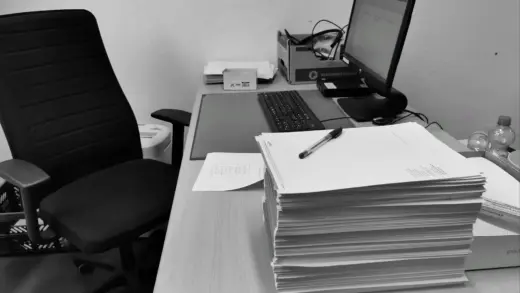 Schreibtisch mit verstreuten Papieren, Dokumenten und einem Computer