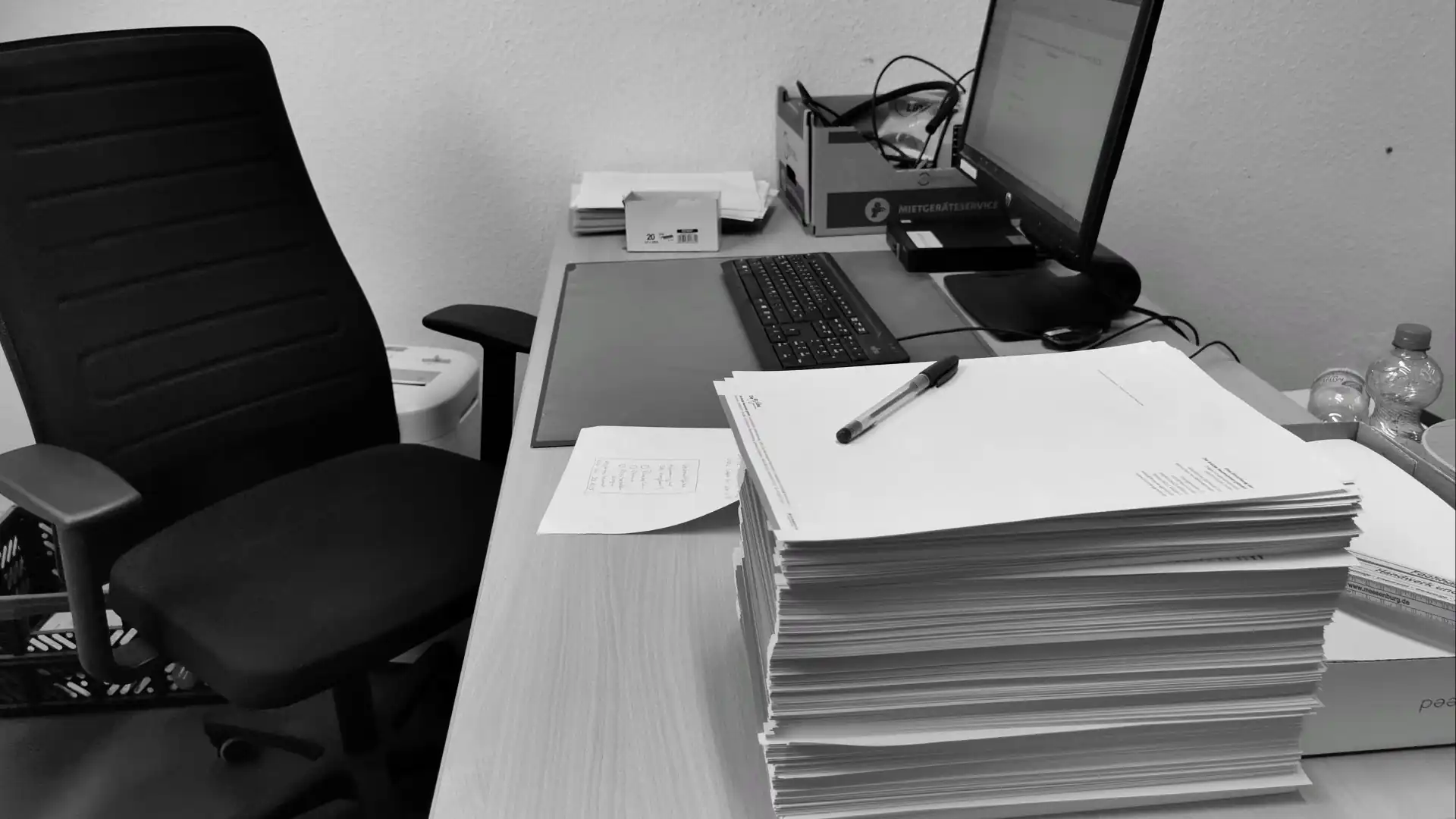 Schreibtisch mit verstreuten Papieren, Dokumenten und einem Computer