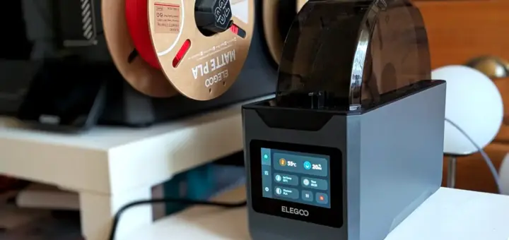 Elegoo H1 HT Filamenttrockner trocknet PLA bei 55 °C, im Hintergrund offen hängende Filamentspulen