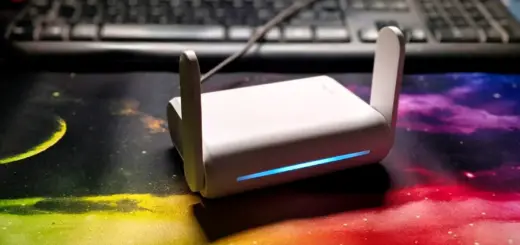 GL.iNet Opal GL-SFT1200 Reiserouter mit aufgeklappten Antennen und blau leuchtender LED auf einem Schreibtisch