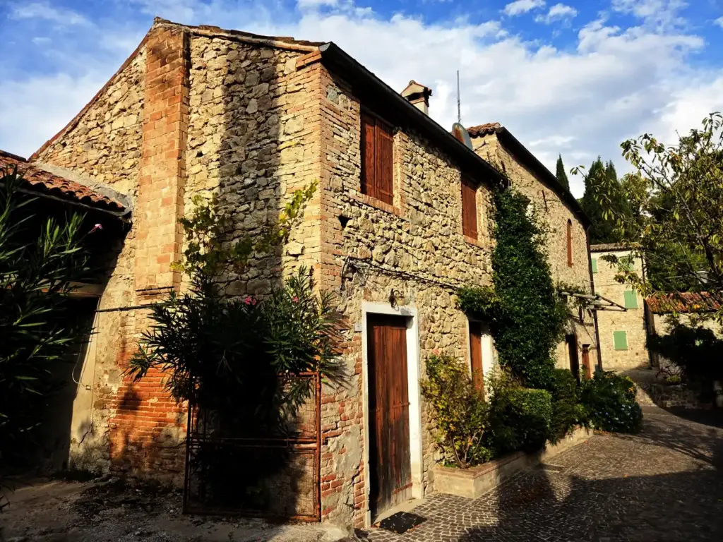 Altes Steinhaus mit Holzfensterläden, Oleander und Kopfsteinpflaster in einem italienischen Dorf namens Arqua Petrarca