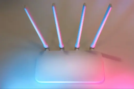 Weißer WLAN-Router mit vier Antennen vor farbigem Hintergrund