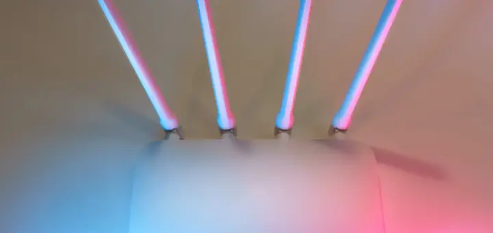 Weißer WLAN-Router mit vier Antennen vor farbigem Hintergrund